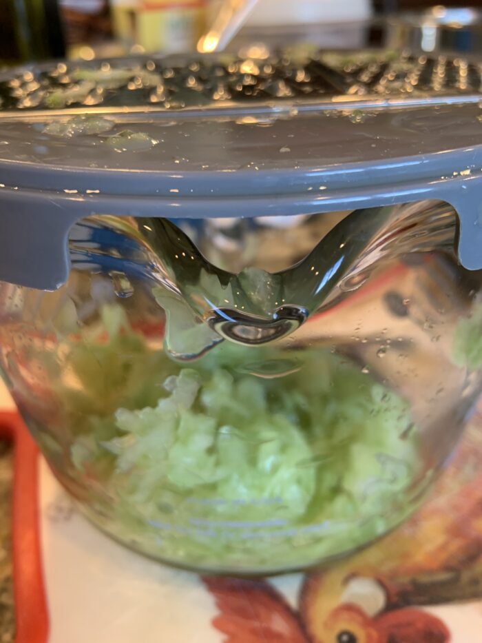 shredded cucumber in pyrex bowl with shredder